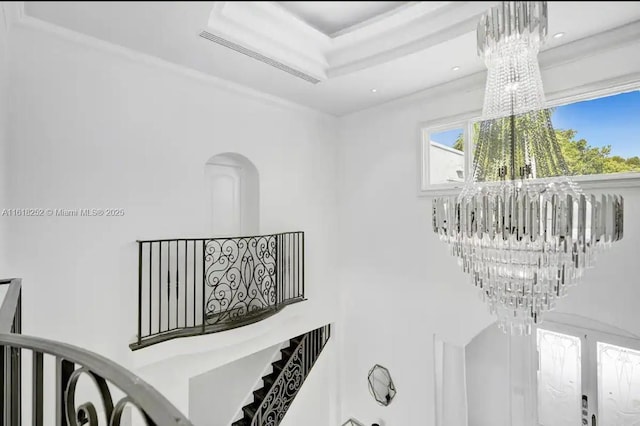 stairs featuring a tray ceiling and a notable chandelier