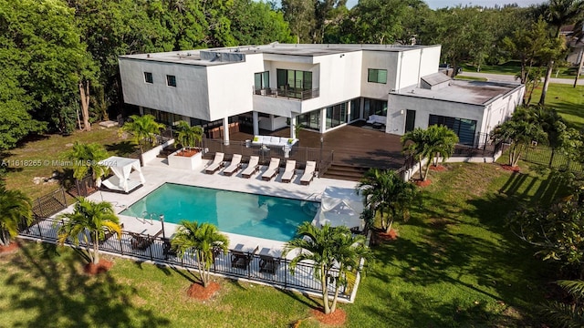 rear view of property with a fenced in pool, a patio area, a balcony, and a lawn