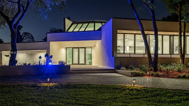 back house at night with a garage and french doors