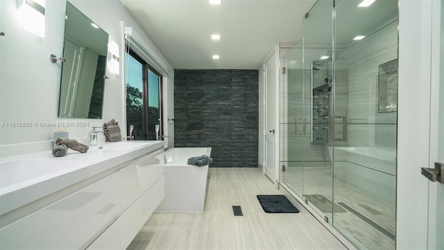 bathroom with independent shower and bath, vanity, and tile walls