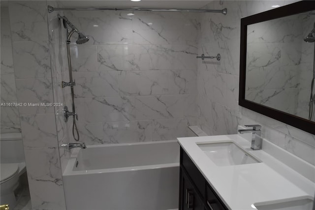 full bathroom with vanity, toilet, tiled shower / bath, and tile walls