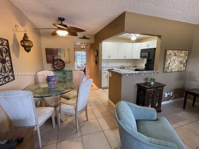 tiled dining space with ceiling fan and a textured ceiling