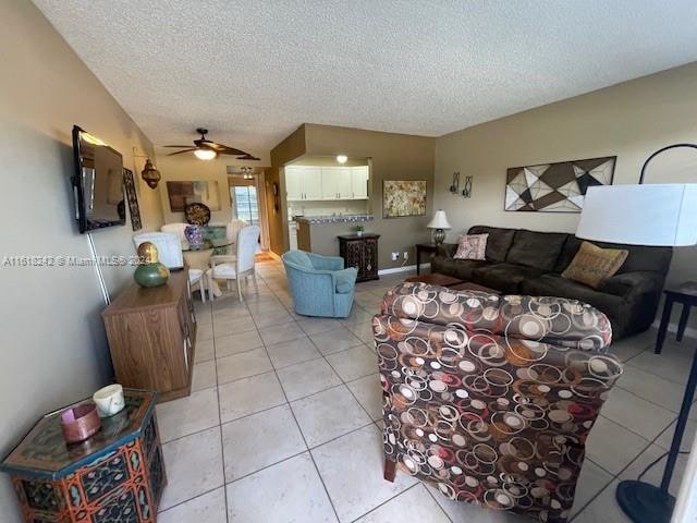 living room featuring ceiling fan, light tile patterned floors, and a textured ceiling