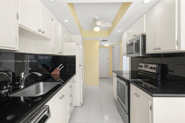 kitchen with white cabinetry, tasteful backsplash, ceiling fan, a tray ceiling, and stainless steel appliances