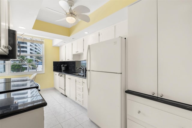 kitchen featuring white appliances, light tile patterned flooring, white cabinetry, ceiling fan, and a raised ceiling