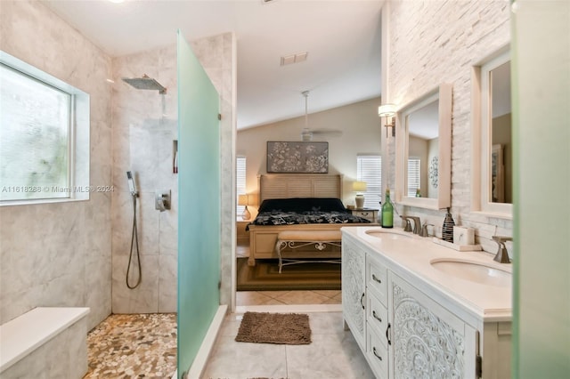 bathroom featuring a tile shower, lofted ceiling, tile patterned flooring, and vanity