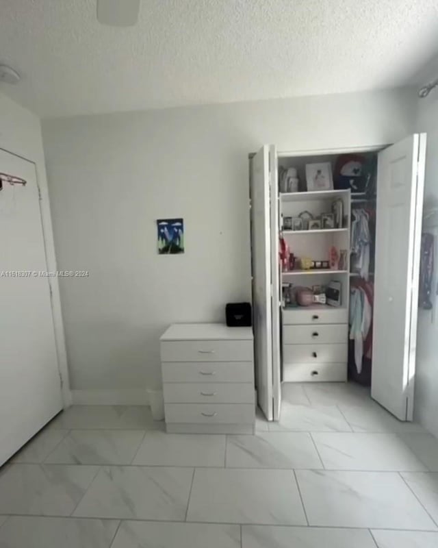 unfurnished bedroom featuring a textured ceiling and light tile patterned floors