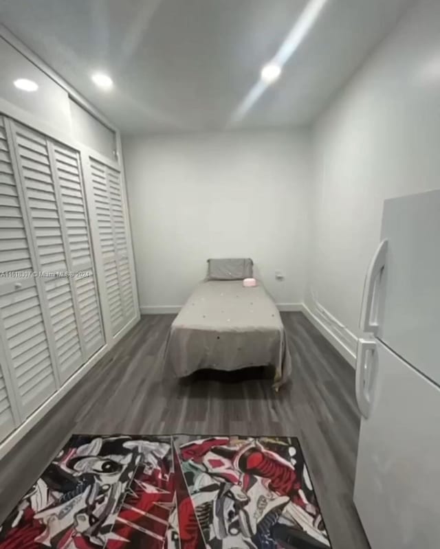 bedroom with dark wood-type flooring and white refrigerator