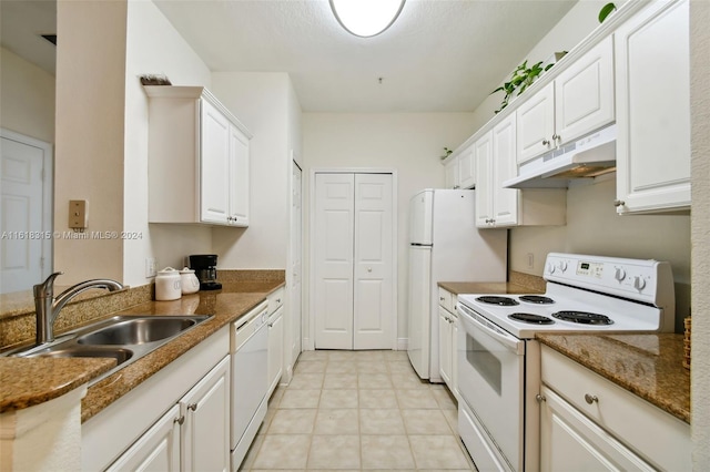 kitchen featuring dark stone countertops, white cabinets, white appliances, light tile patterned floors, and sink