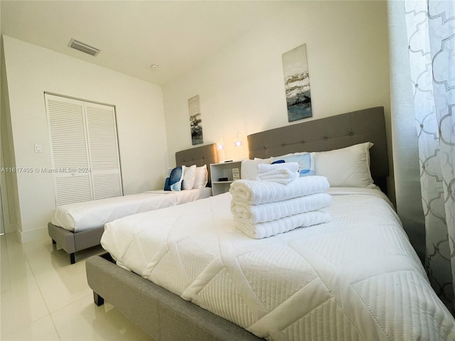 bedroom with tile patterned floors and a closet