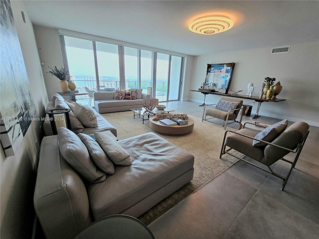 living room featuring concrete flooring, expansive windows, and a water view