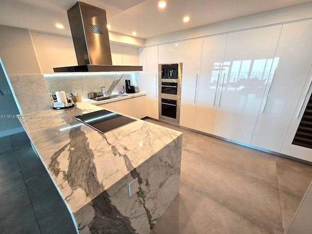 kitchen with appliances with stainless steel finishes, sink, white cabinets, island exhaust hood, and light stone countertops