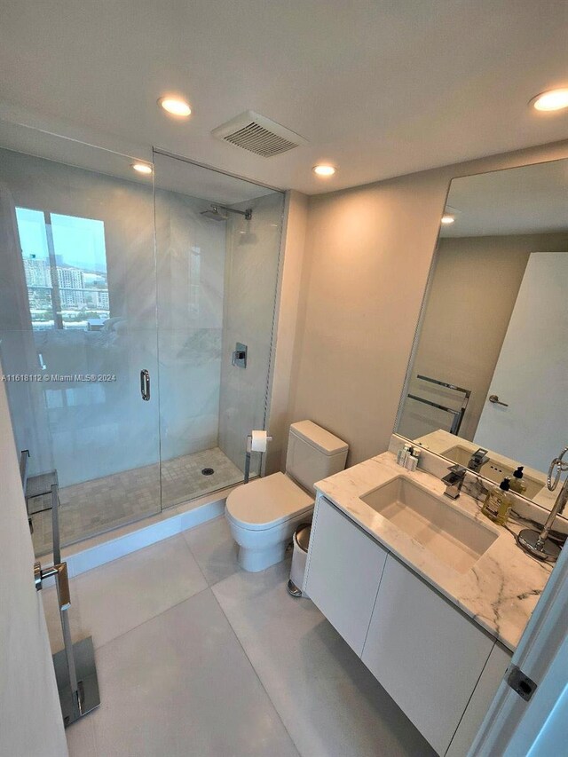 bathroom featuring tile patterned floors, vanity, an enclosed shower, and toilet