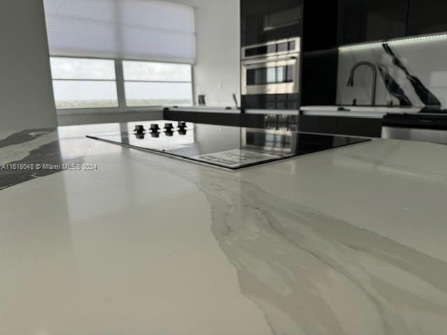 kitchen with oven, concrete flooring, and black electric cooktop