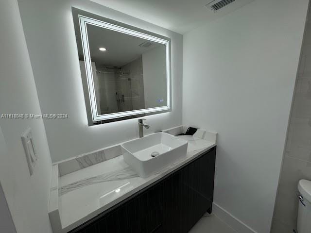 bathroom featuring vanity, toilet, and a tile shower