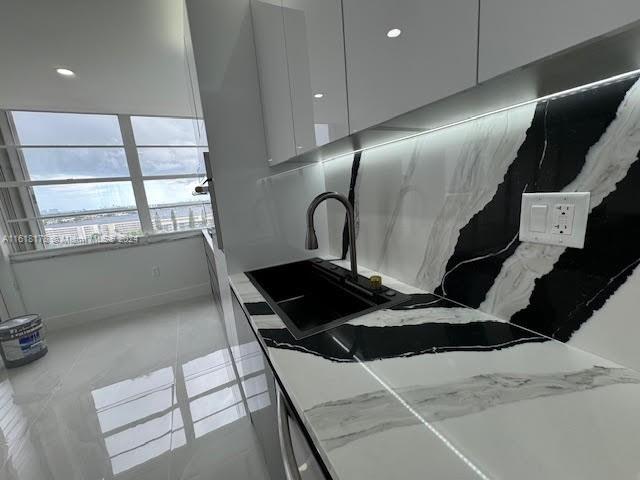 kitchen featuring tile patterned floors, light stone countertops, and sink