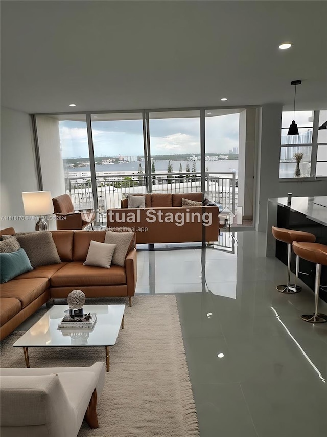 living room with a water view, tile patterned flooring, and a wall of windows