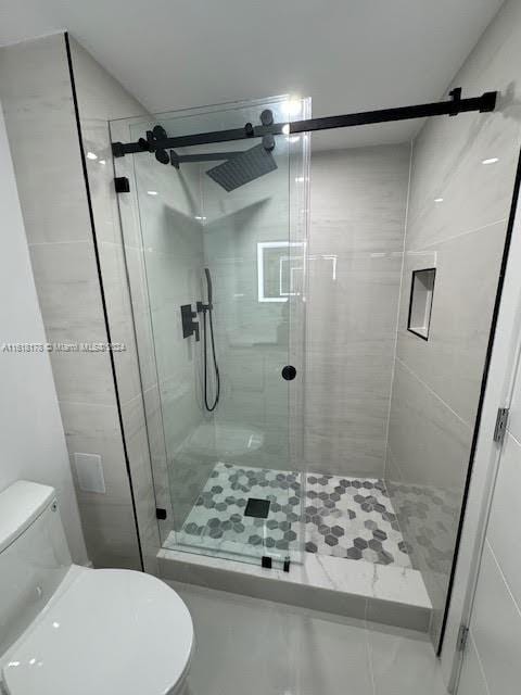 bathroom featuring a shower with shower door and toilet