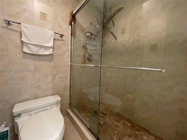 bathroom featuring walk in shower, tile walls, and toilet