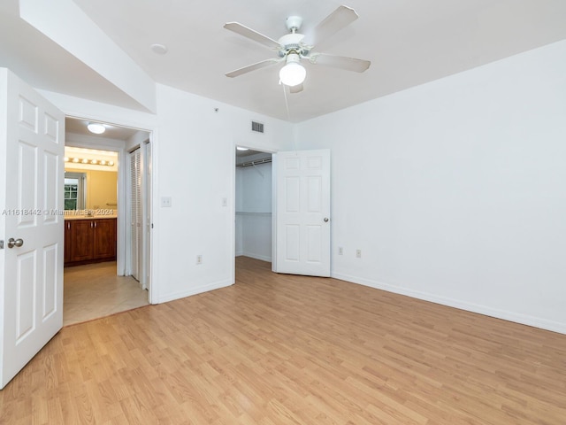 unfurnished bedroom featuring a spacious closet, ceiling fan, a closet, ensuite bathroom, and light tile patterned flooring