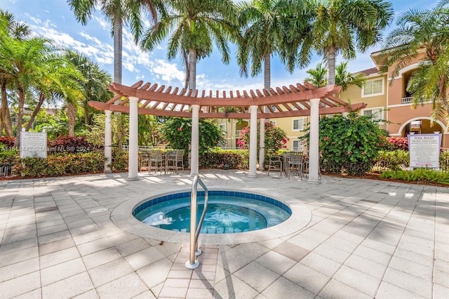 view of pool featuring a community hot tub, a pergola, and a patio