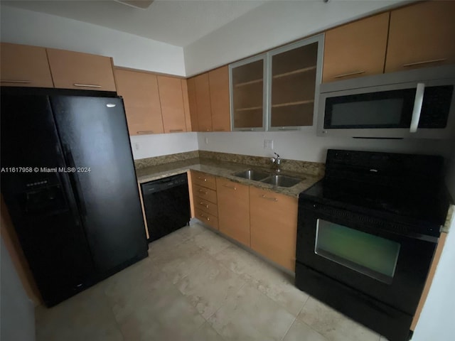 kitchen featuring light tile patterned floors, black appliances, stone counters, and sink