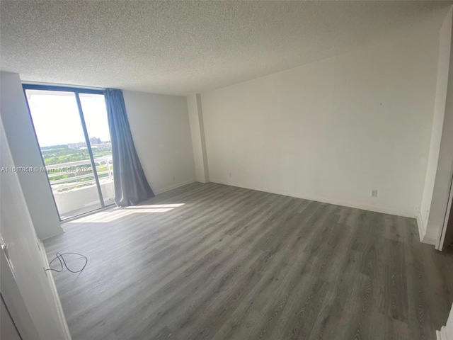 unfurnished room featuring dark wood-type flooring, floor to ceiling windows, and a textured ceiling