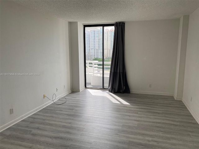 spare room featuring expansive windows, a textured ceiling, and hardwood / wood-style floors