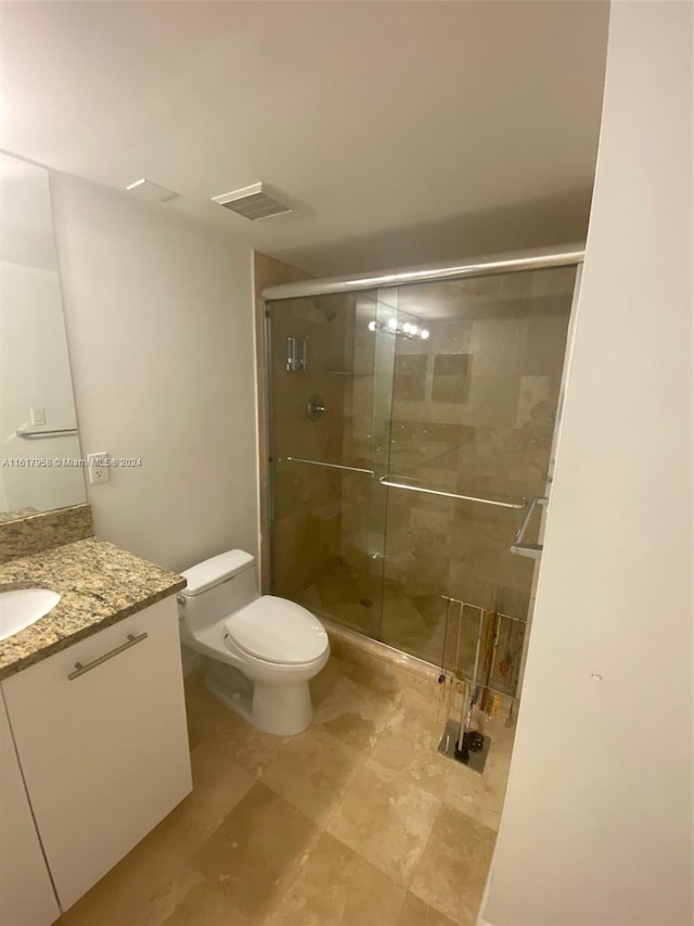 bathroom with vanity, toilet, tile patterned flooring, and an enclosed shower