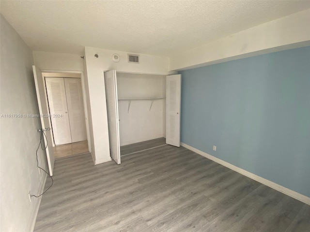 unfurnished bedroom featuring a textured ceiling, a closet, and wood-type flooring