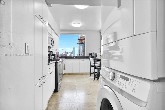 clothes washing area featuring stacked washer / drying machine, sink, and light tile patterned floors