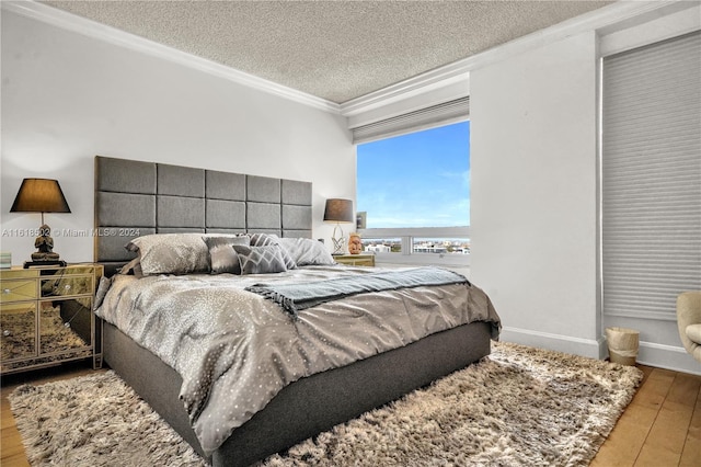 bedroom with ornamental molding, hardwood / wood-style floors, and a textured ceiling