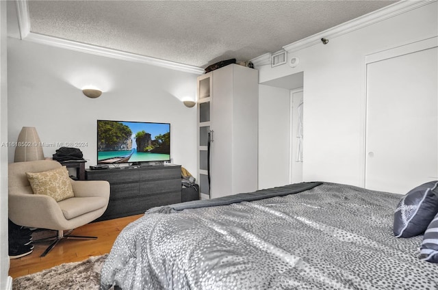 bedroom featuring ornamental molding, a textured ceiling, and hardwood / wood-style flooring