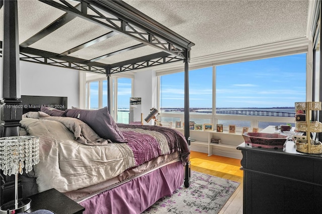 bedroom with a water view, a textured ceiling, and hardwood / wood-style floors