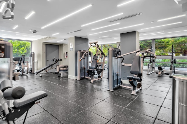 gym featuring dark tile patterned floors and floor to ceiling windows