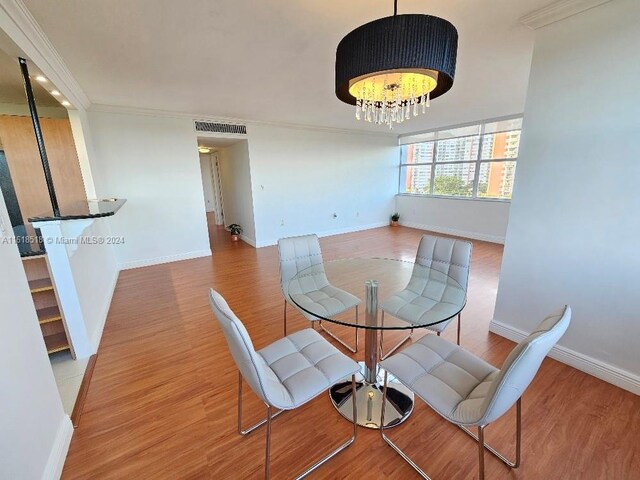 dining room with hardwood / wood-style flooring, a notable chandelier, and crown molding