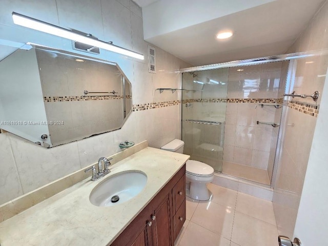 bathroom featuring toilet, tile walls, a shower with shower door, and vanity