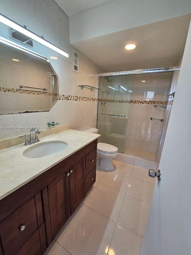 bathroom with vanity, toilet, tile patterned floors, a shower with door, and decorative backsplash