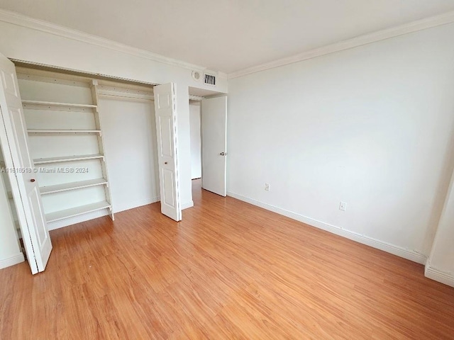 unfurnished bedroom featuring ornamental molding, light hardwood / wood-style flooring, and a closet