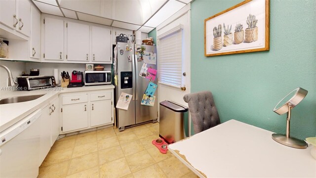 kitchen with stainless steel appliances, white cabinetry, sink, and a paneled ceiling