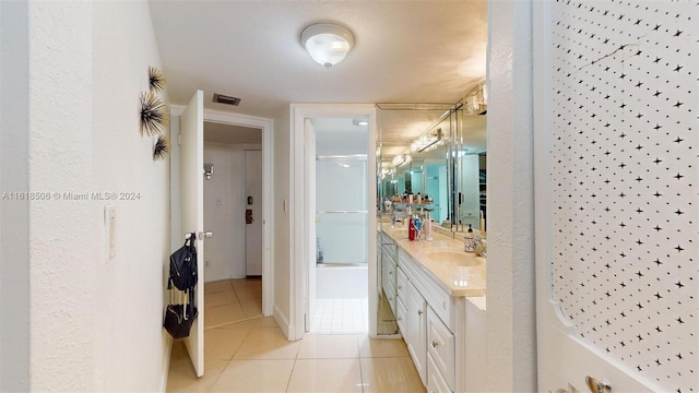 bathroom with walk in shower, vanity, and tile patterned flooring