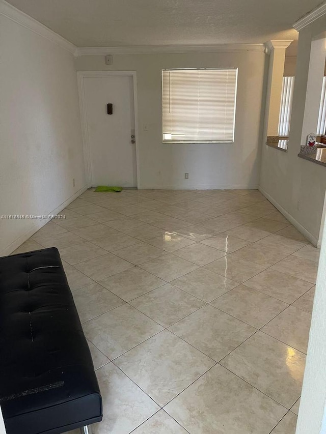 tiled spare room featuring plenty of natural light and ornamental molding