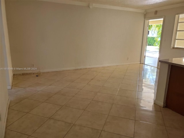 tiled empty room with crown molding and a textured ceiling