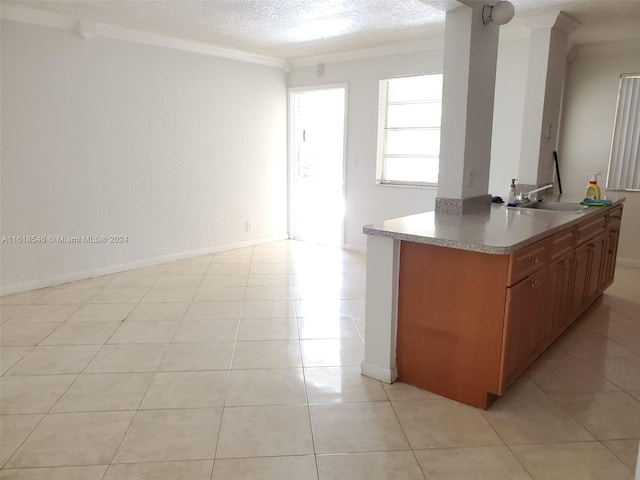 kitchen featuring ornamental molding, sink, light tile patterned flooring, and a textured ceiling