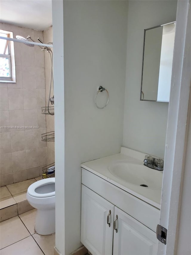 bathroom featuring vanity, a tile shower, tile patterned flooring, and toilet