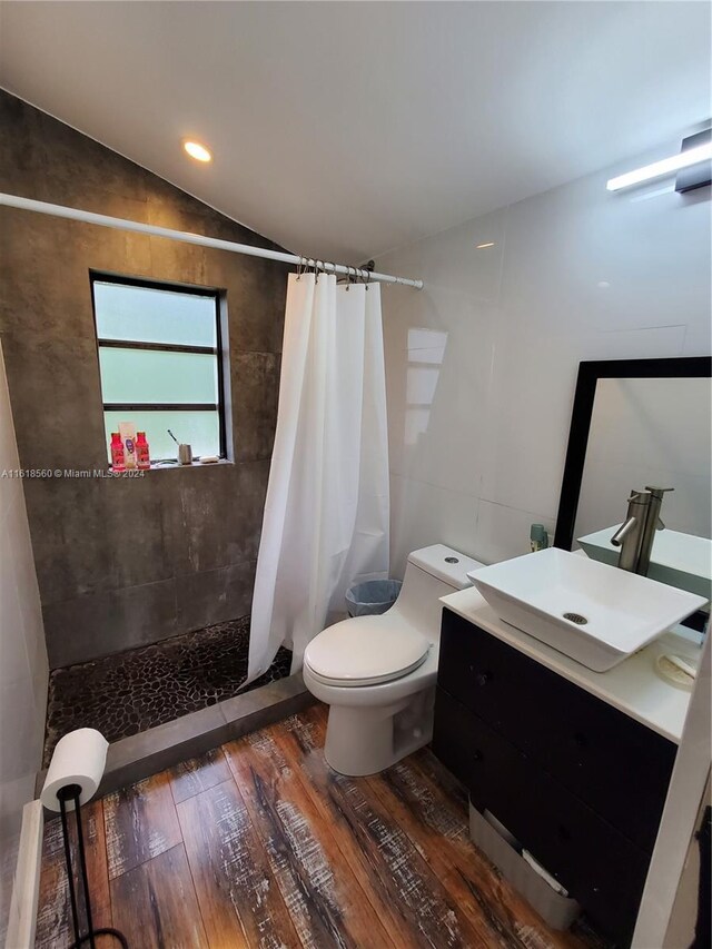 bathroom with vanity, lofted ceiling, hardwood / wood-style flooring, toilet, and curtained shower