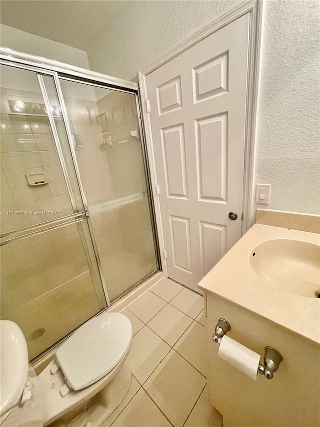 bathroom with tile patterned floors, vanity, walk in shower, and toilet