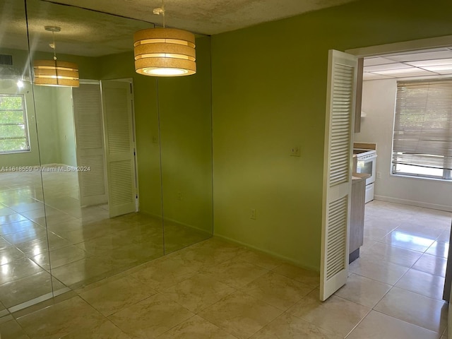 spare room with a textured ceiling and light tile patterned floors