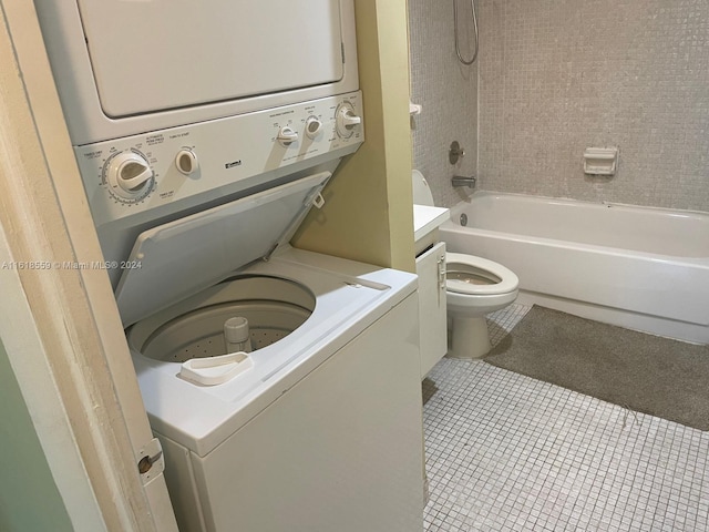 full bathroom featuring tile patterned flooring, toilet, stacked washer and dryer, vanity, and tiled shower / bath combo