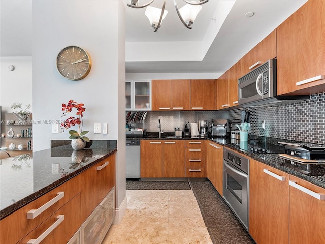 kitchen featuring a notable chandelier, stainless steel appliances, decorative backsplash, pendant lighting, and a kitchen bar